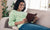 Women laying on couch reading a book wearing a pair of ICU Eyewear reading glasses.